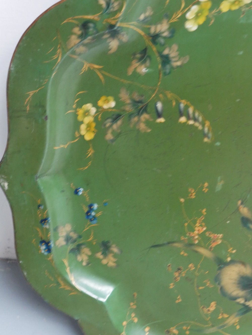 An antique 19th-century olive green painted metal toleware tray featuring a scalloped rim and hand-painted botanical flowers with gilded accents. View IV