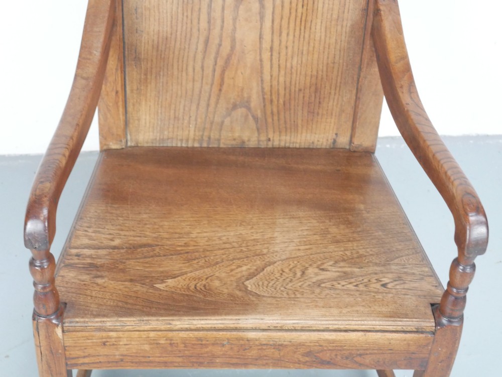 An early 19th-century country oak armchair featuring a high panelled backrest, curved arms, turned front supports, and a square stretcher base. View IV