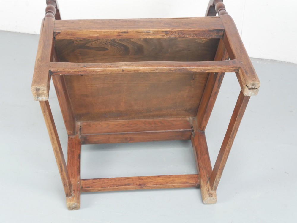 An early 19th-century country oak armchair featuring a high panelled backrest, curved arms, turned front supports, and a square stretcher base. View IX