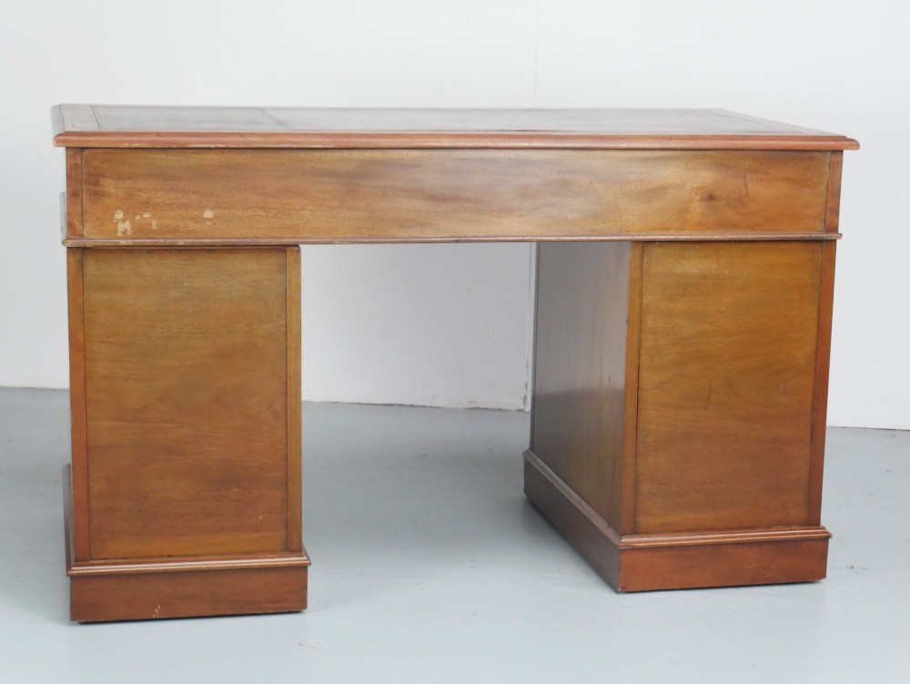 An Edwardian mahogany kneehole pedestal desk featuring an inset writing top, inlaid drawer borders, and nine drawers fitted with brass swan-neck handles. View VIII