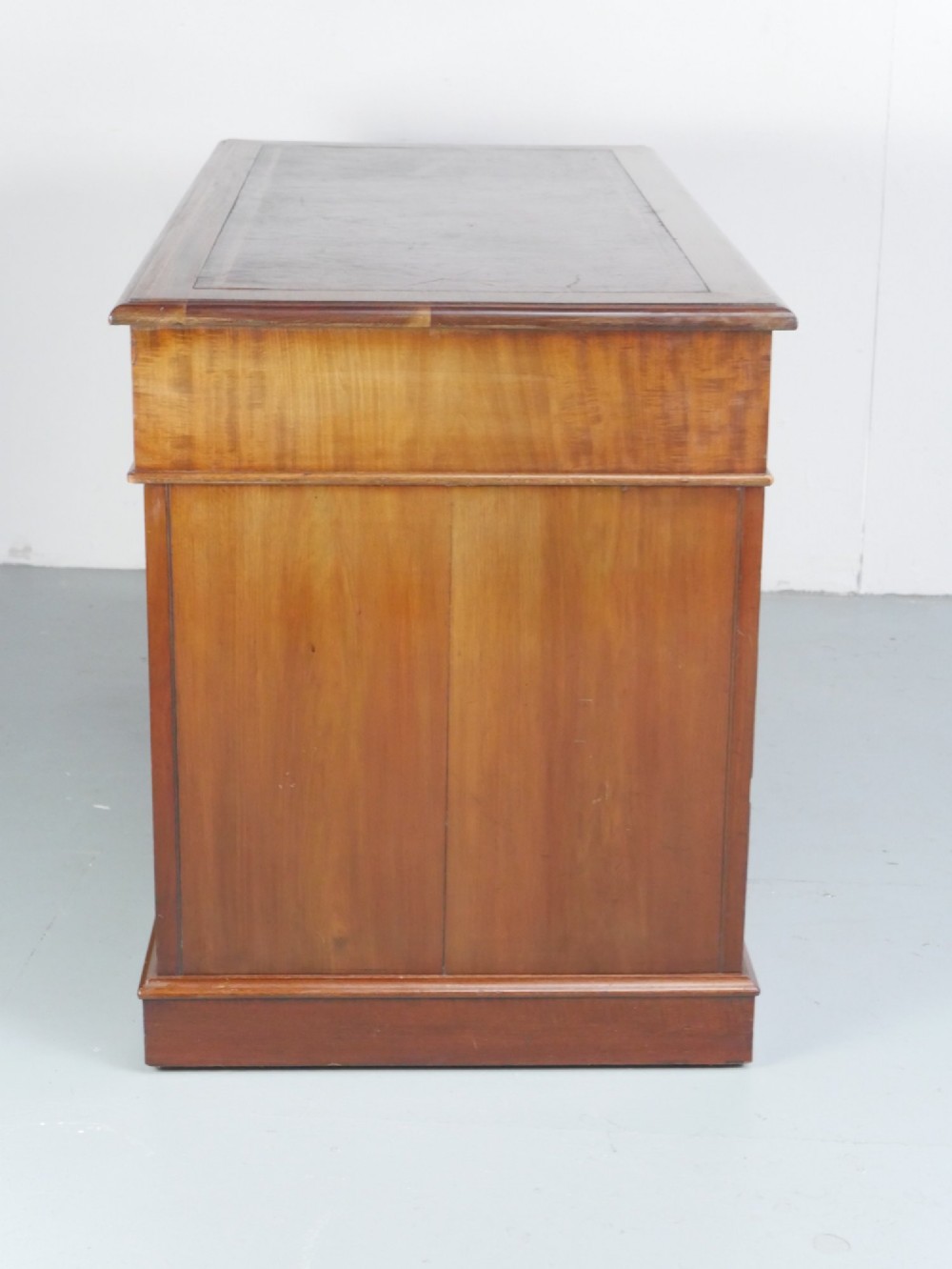 An Edwardian mahogany kneehole pedestal desk featuring an inset writing top, inlaid drawer borders, and nine drawers fitted with brass swan-neck handles. View IX