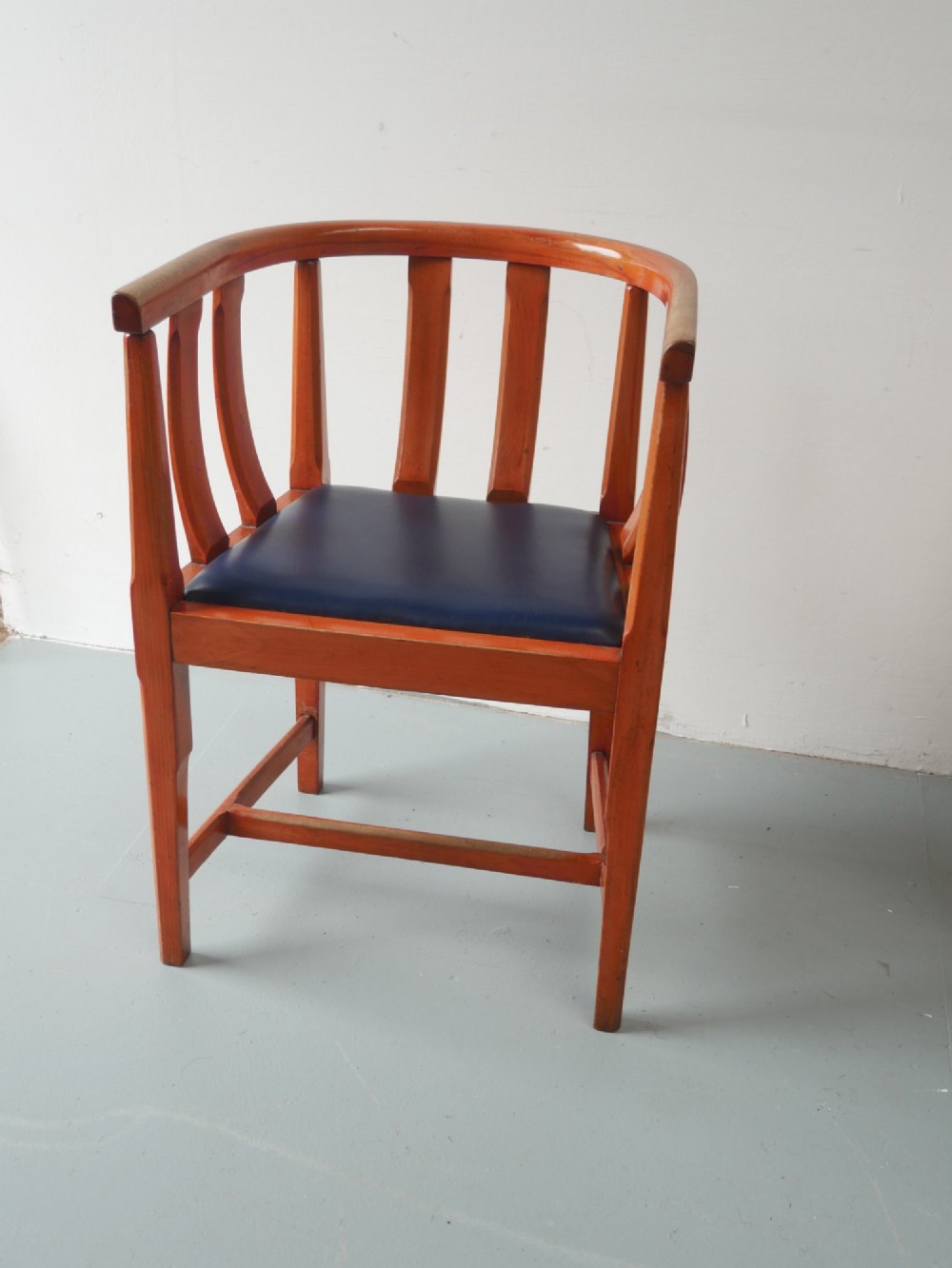 A pair of warm brown hardwood tub armchairs featuring curved slatted backrests and navy blue upholstered seats. View II
