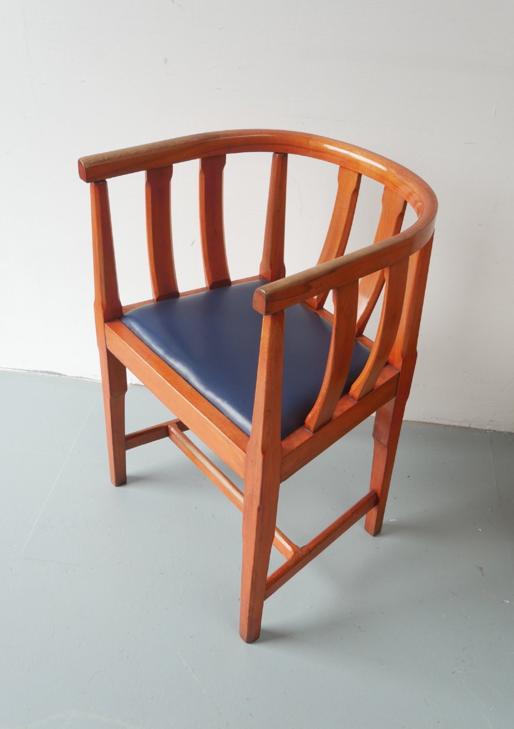 A pair of warm brown hardwood tub armchairs featuring curved slatted backrests and navy blue upholstered seats. View III