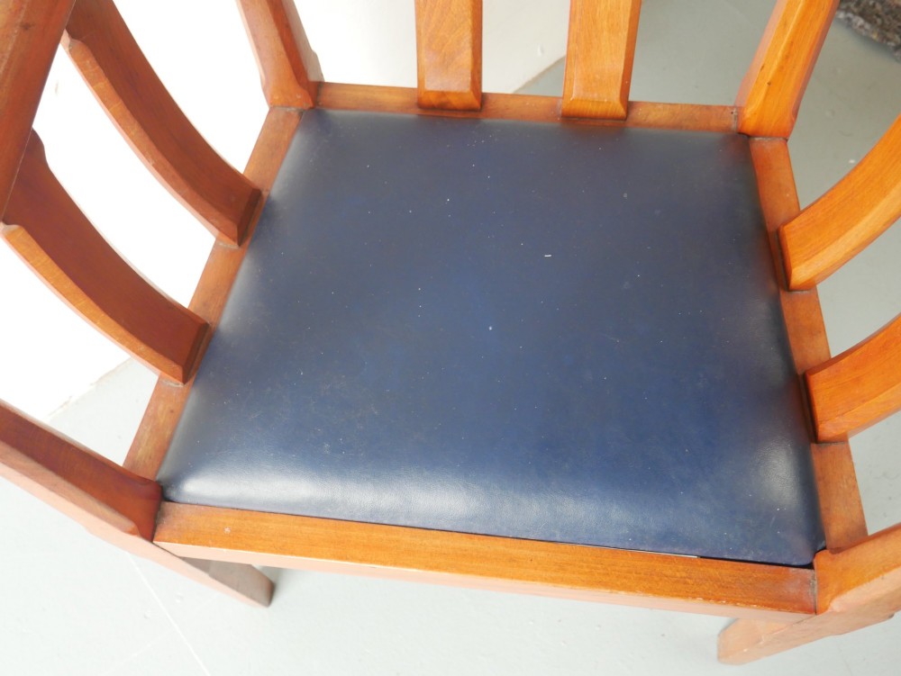A pair of warm brown hardwood tub armchairs featuring curved slatted backrests and navy blue upholstered seats. View V
