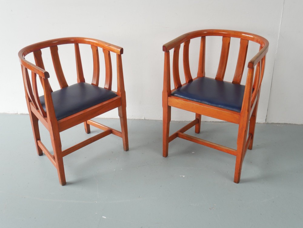 A pair of warm brown hardwood tub armchairs featuring curved slatted backrests and navy blue upholstered seats. View XI