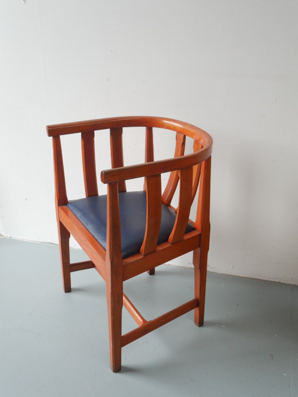 A pair of warm brown hardwood tub armchairs featuring curved slatted backrests and navy blue upholstered seats. View XII