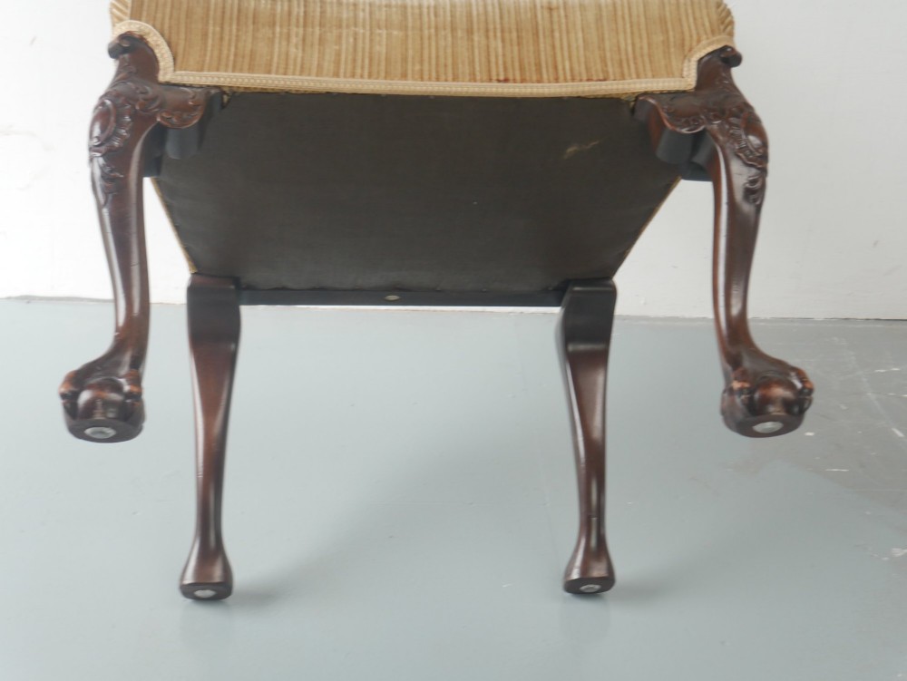 A carved mahogany armchair featuring an ornate pierced splat back, scrolled arms, tan striped fabric upholstery, and cabriole front legs with claw-and-ball feet. View VII
