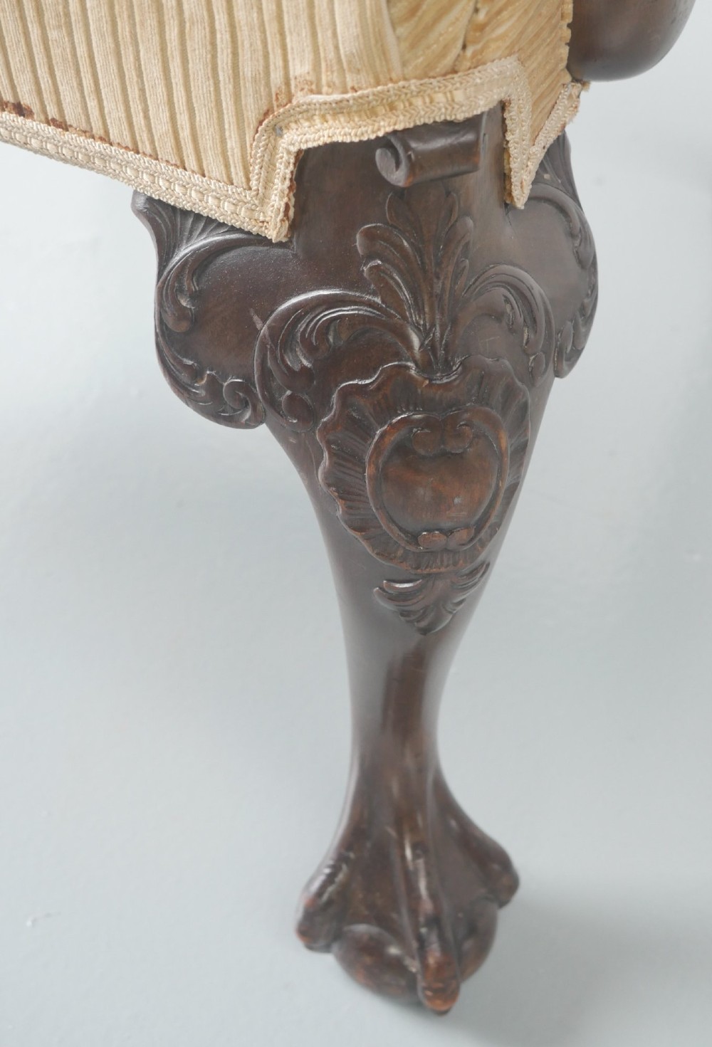 A carved mahogany armchair featuring an ornate pierced splat back, scrolled arms, tan striped fabric upholstery, and cabriole front legs with claw-and-ball feet. View XII