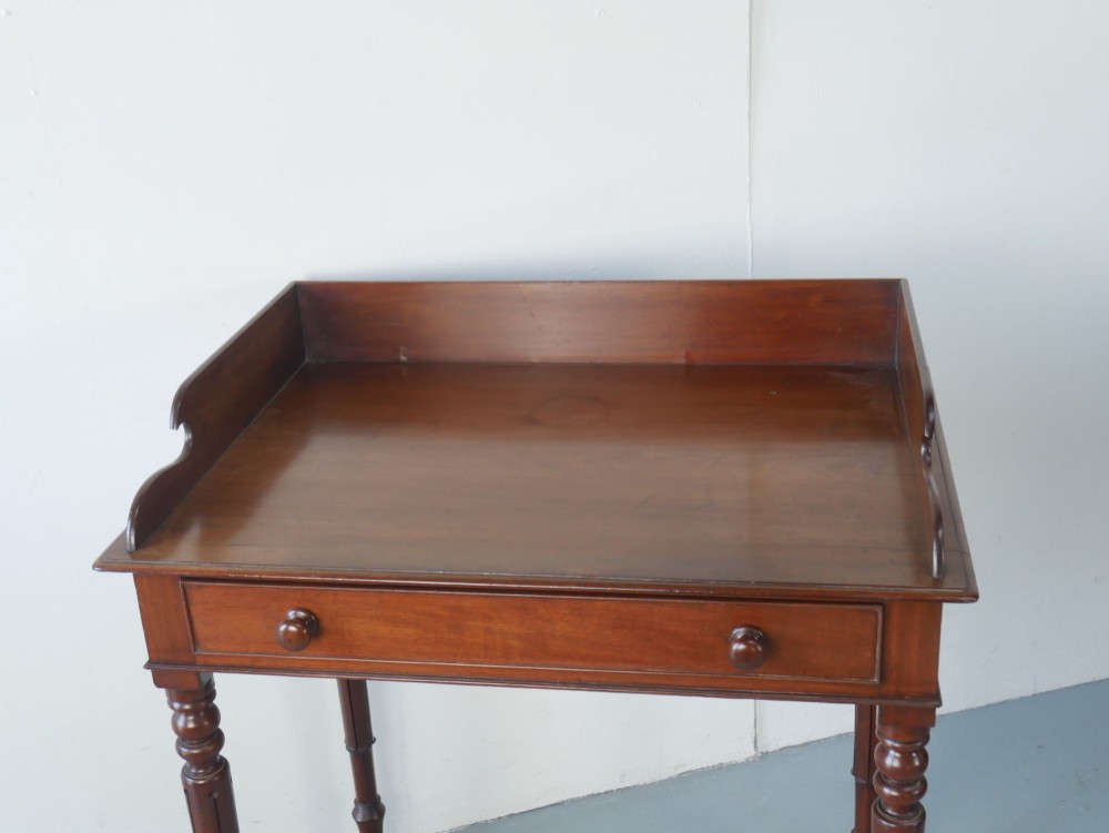 A 19th-century mahogany writing table featuring turned legs, a single frieze drawer with wooden knobs, and a raised gallery back. View II