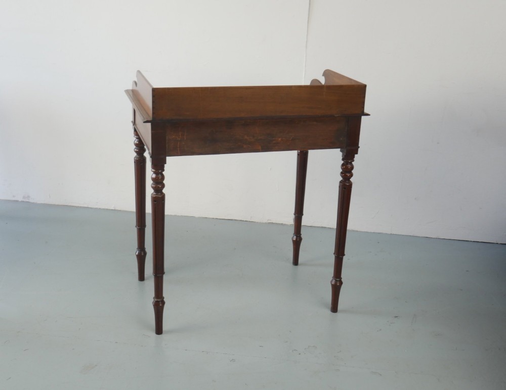 A 19th-century mahogany writing table featuring turned legs, a single frieze drawer with wooden knobs, and a raised gallery back. View IV