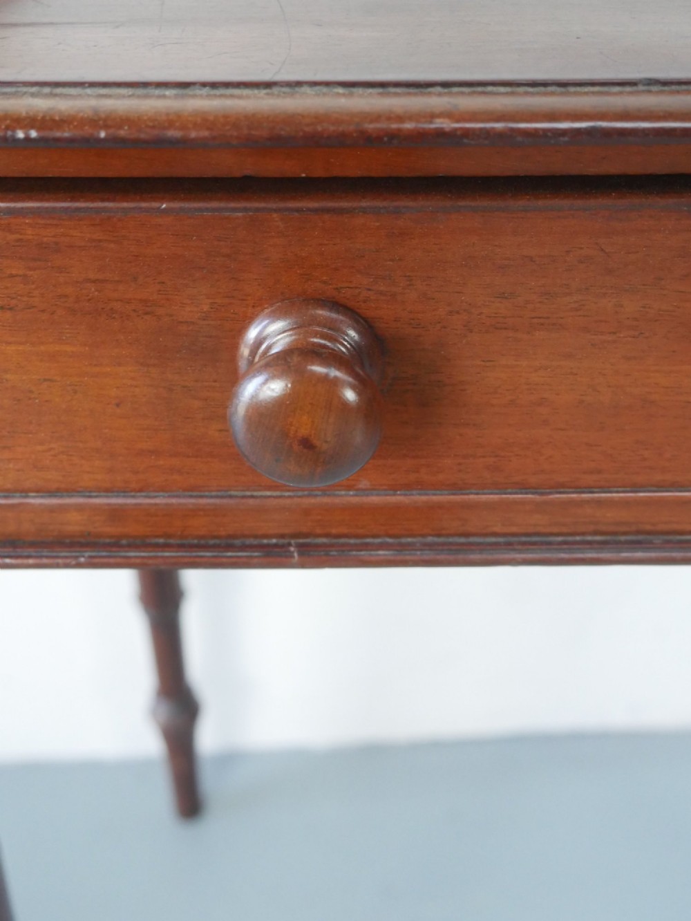 A 19th-century mahogany writing table featuring turned legs, a single frieze drawer with wooden knobs, and a raised gallery back. View IX