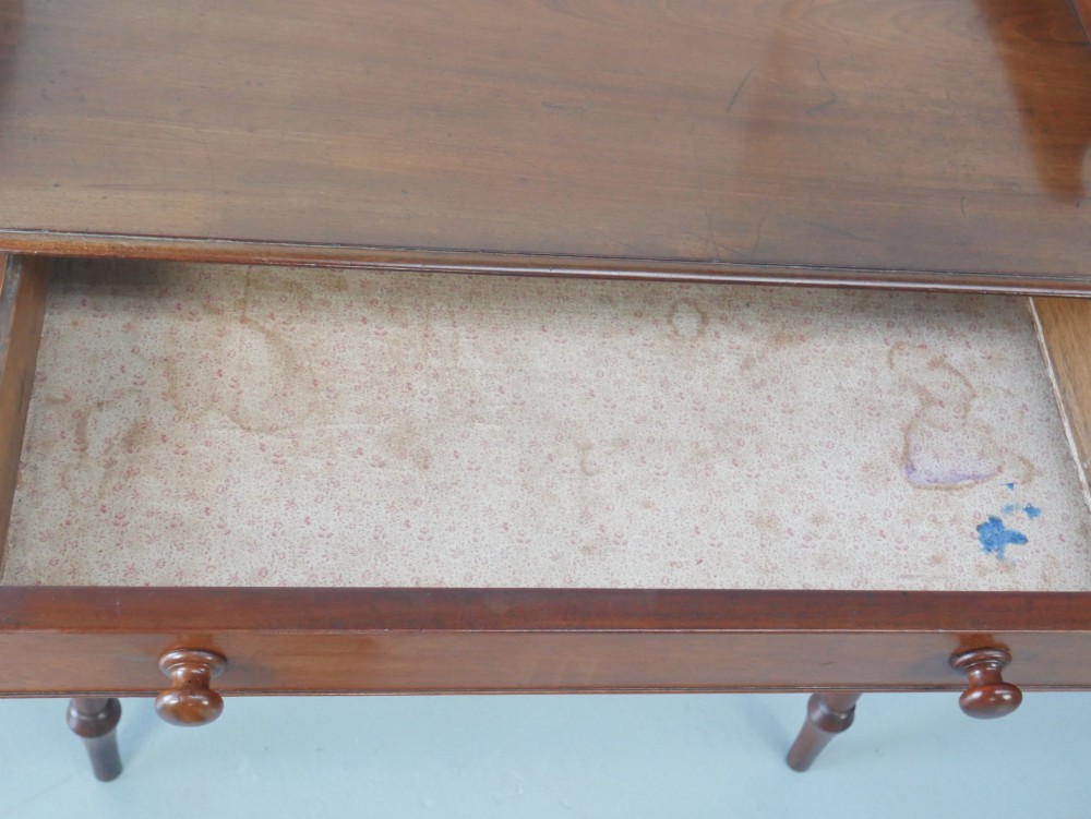 A 19th-century mahogany writing table featuring turned legs, a single frieze drawer with wooden knobs, and a raised gallery back. View X