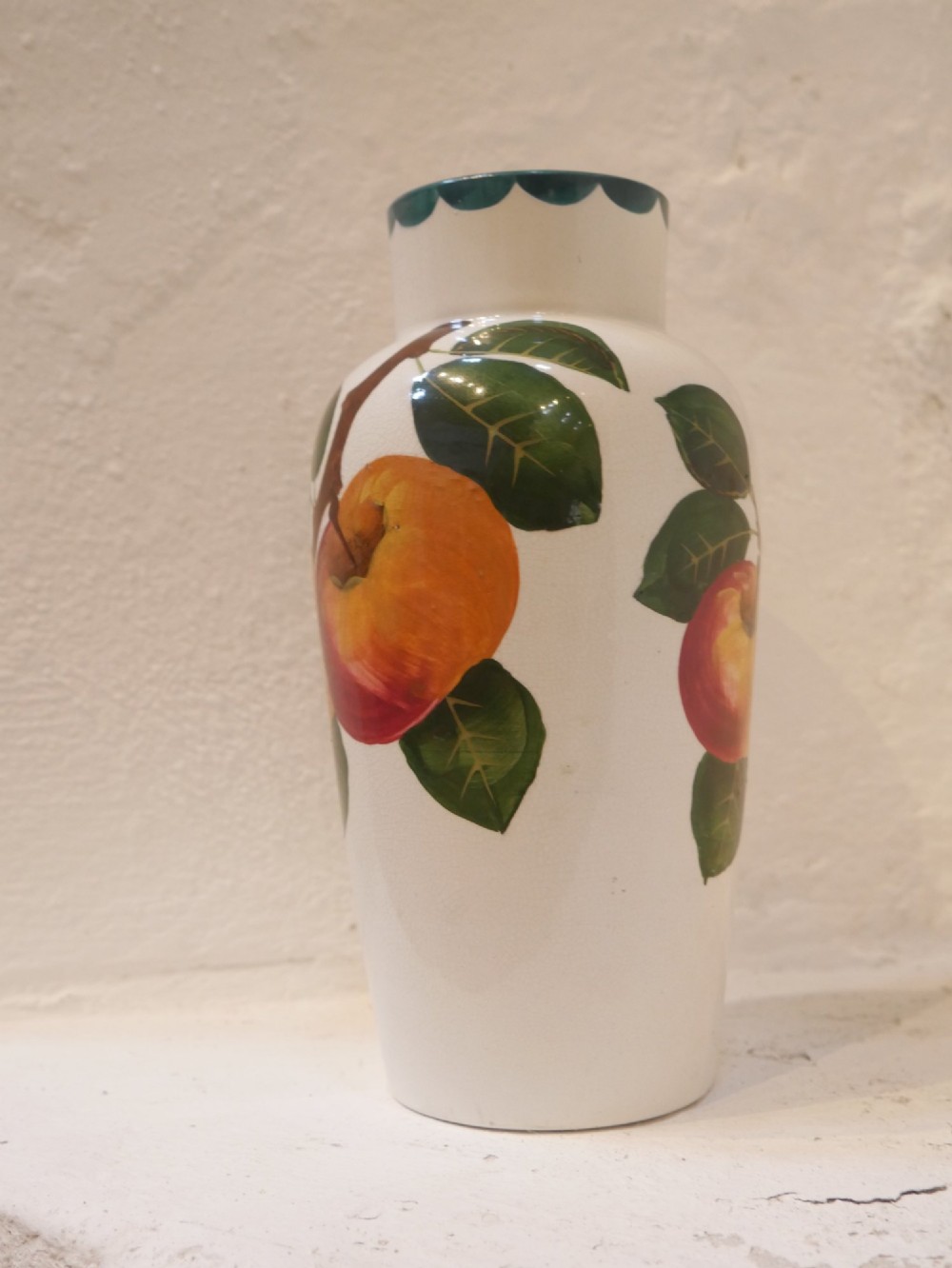 A cylindrical cream earthenware vase hand-painted with green leaves, yellow apples, and a green scalloped rim detail. View II
