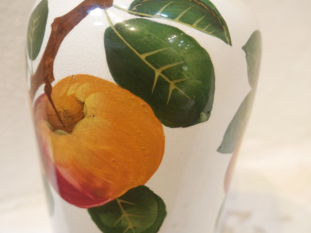 A cylindrical cream earthenware vase hand-painted with green leaves, yellow apples, and a green scalloped rim detail. View V