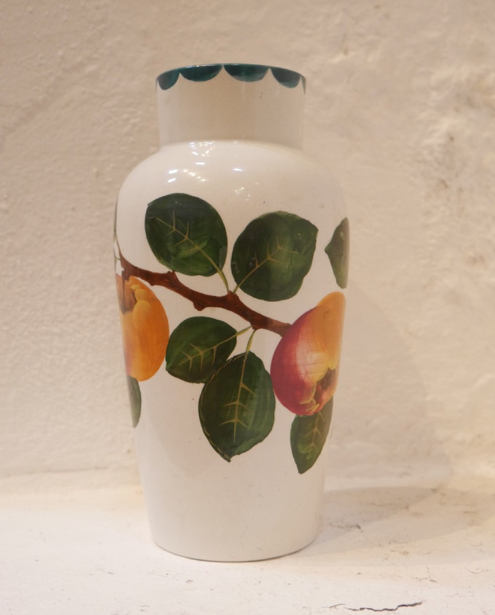 A cylindrical cream earthenware vase hand-painted with green leaves, yellow apples, and a green scalloped rim detail. View VIII
