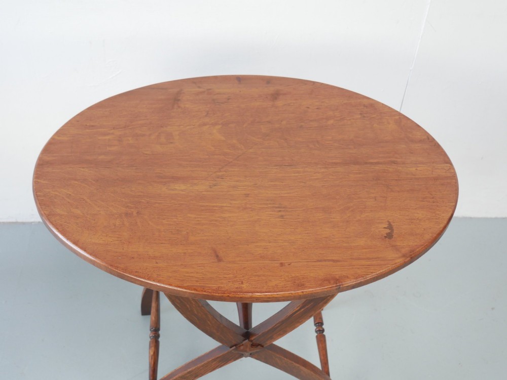 A circular oak lamp table featuring curved cross-framed legs joined by turned stretchers. View III