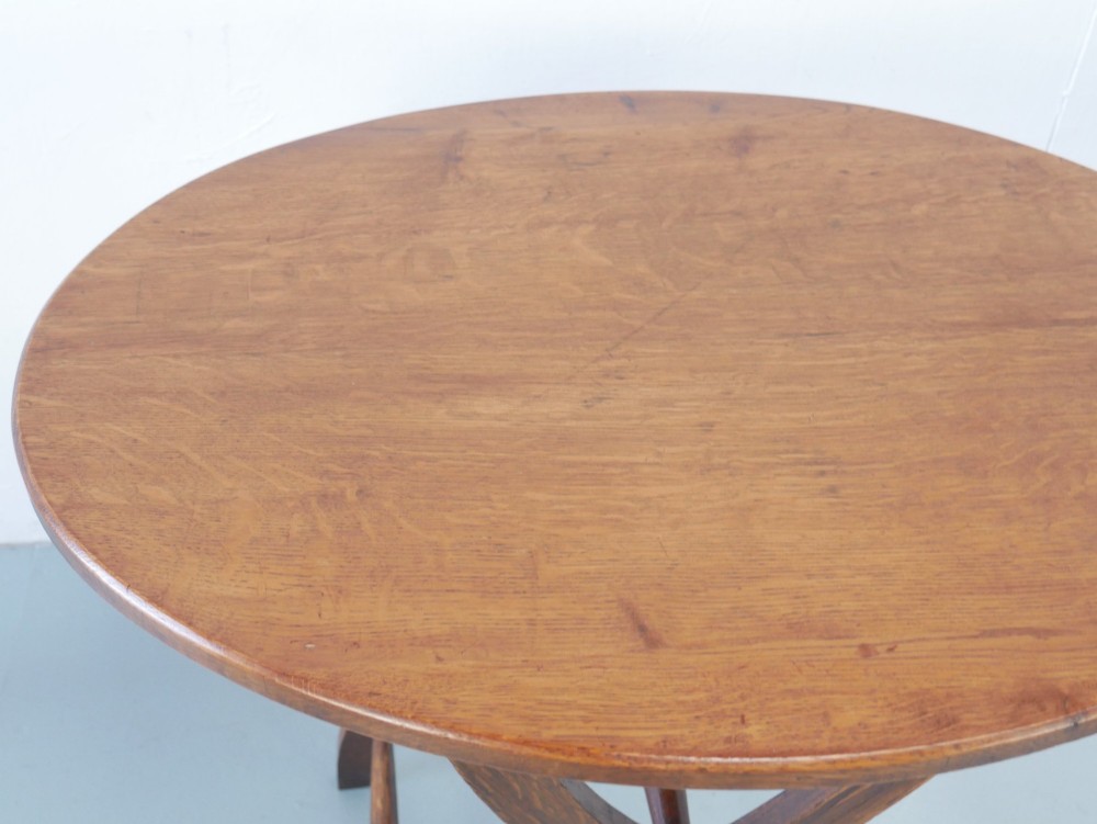 A circular oak lamp table featuring curved cross-framed legs joined by turned stretchers. View V