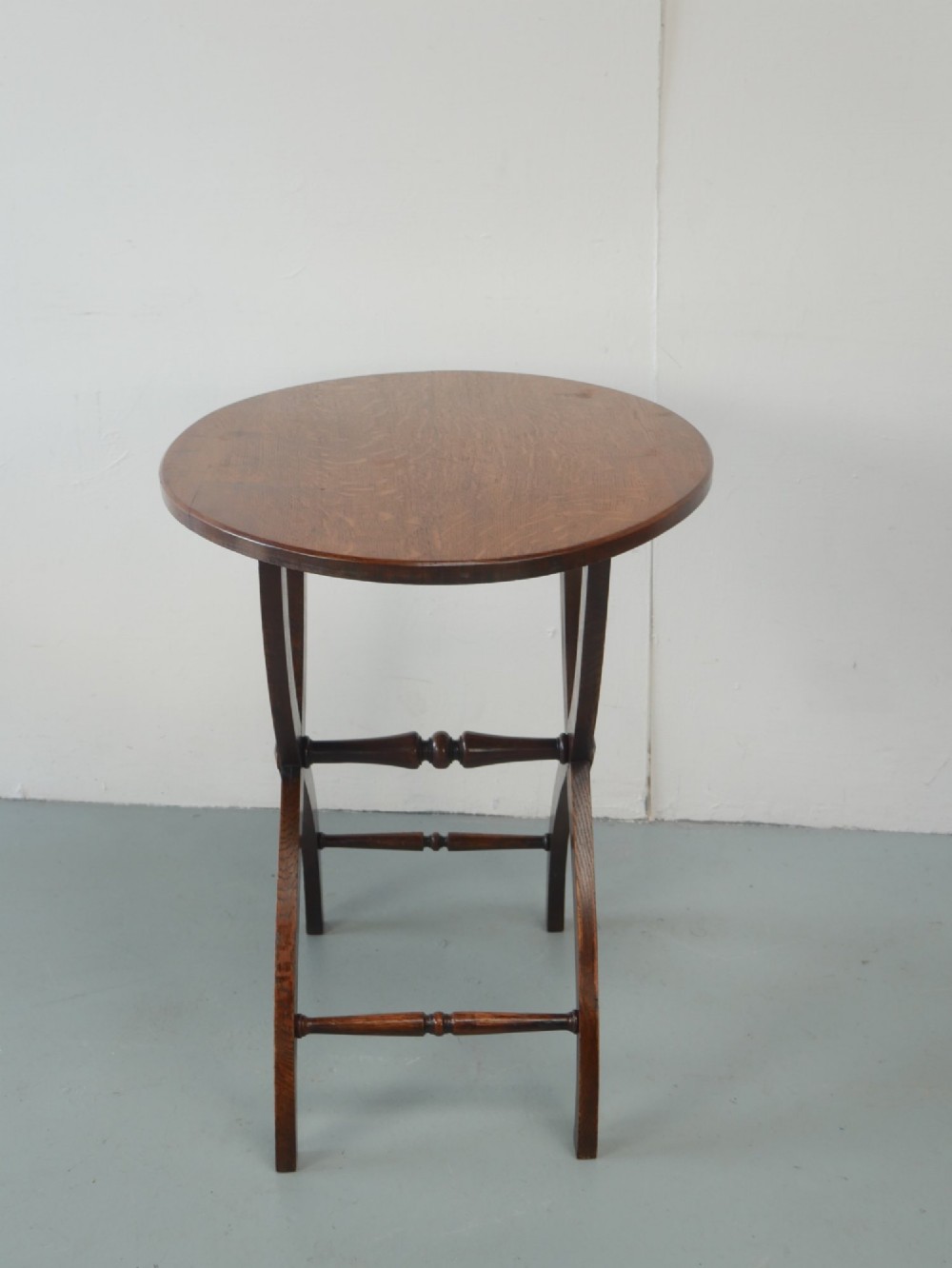 A circular oak lamp table featuring curved cross-framed legs joined by turned stretchers. View IX