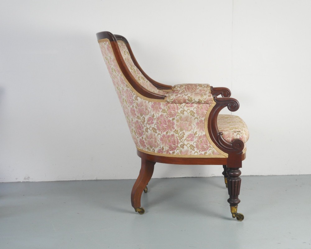 A Regency mahogany armchair with floral patterned fabric upholstery, scroll arms, reeded front legs, and brass castors. View II