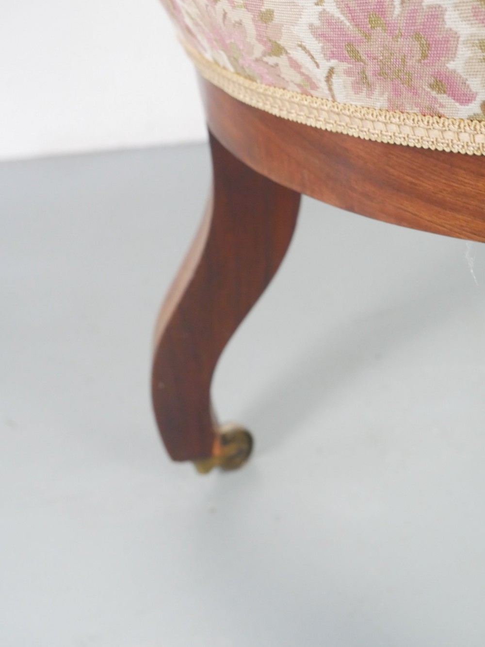 A Regency mahogany armchair with floral patterned fabric upholstery, scroll arms, reeded front legs, and brass castors. View III