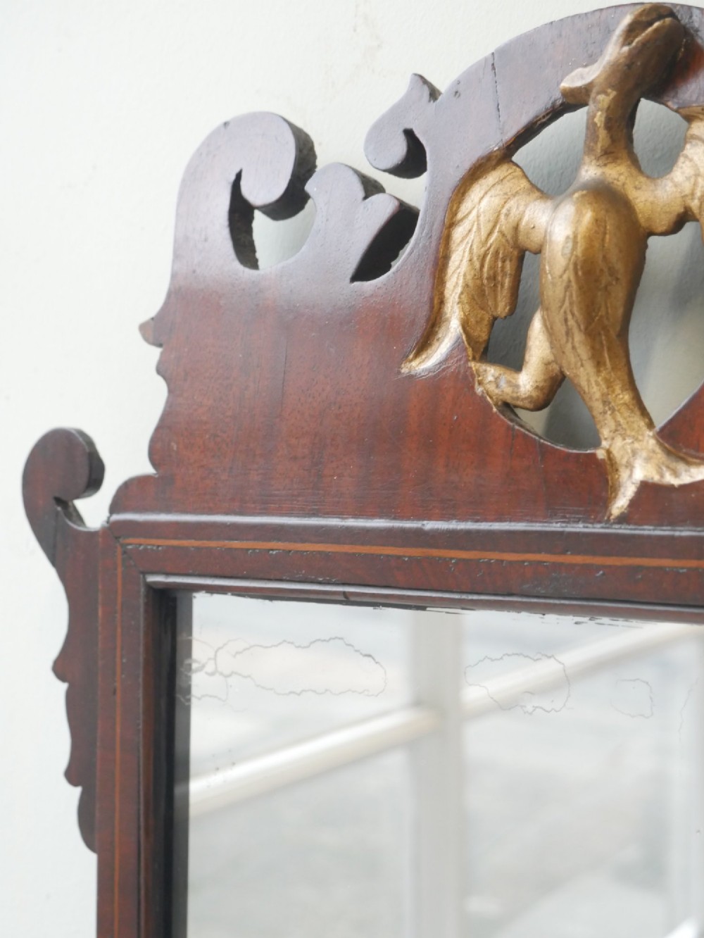 A petit Georgian mahogany wall mirror featuring a pierced fretwork frame topped with a gilded eagle crest. View VI