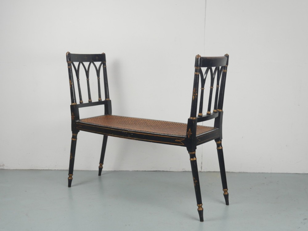 A black painted and parcel-gilt antique Sheraton window seat featuring pointed arch end splats and a floral needlepoint cushion. View II