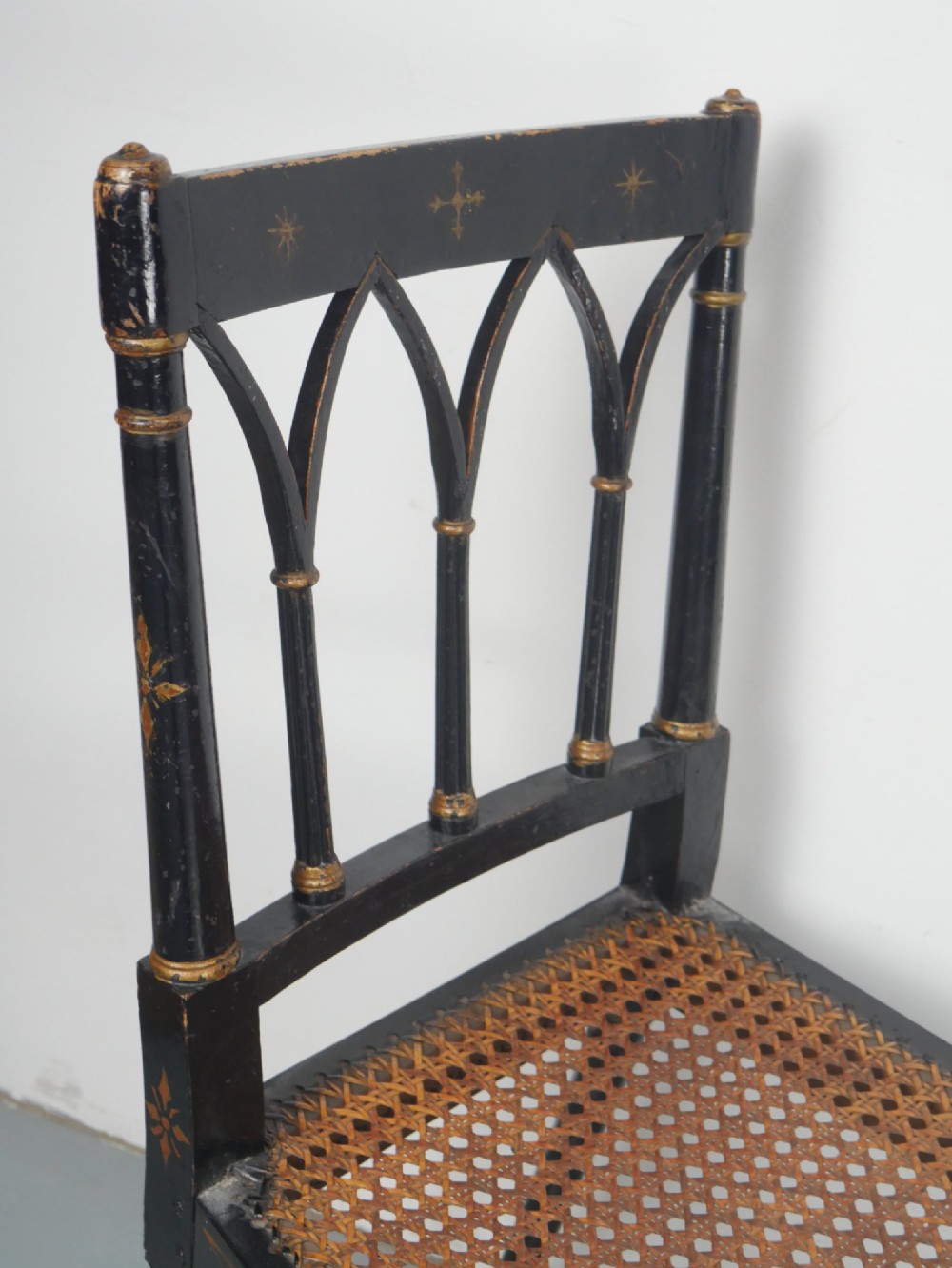 A black painted and parcel-gilt antique Sheraton window seat featuring pointed arch end splats and a floral needlepoint cushion. View III
