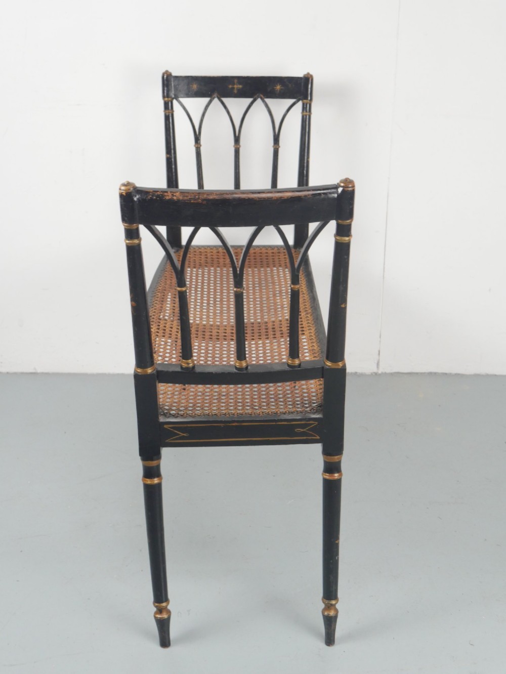 A black painted and parcel-gilt antique Sheraton window seat featuring pointed arch end splats and a floral needlepoint cushion. View V
