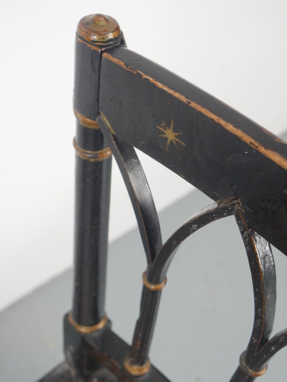 A black painted and parcel-gilt antique Sheraton window seat featuring pointed arch end splats and a floral needlepoint cushion. View VII