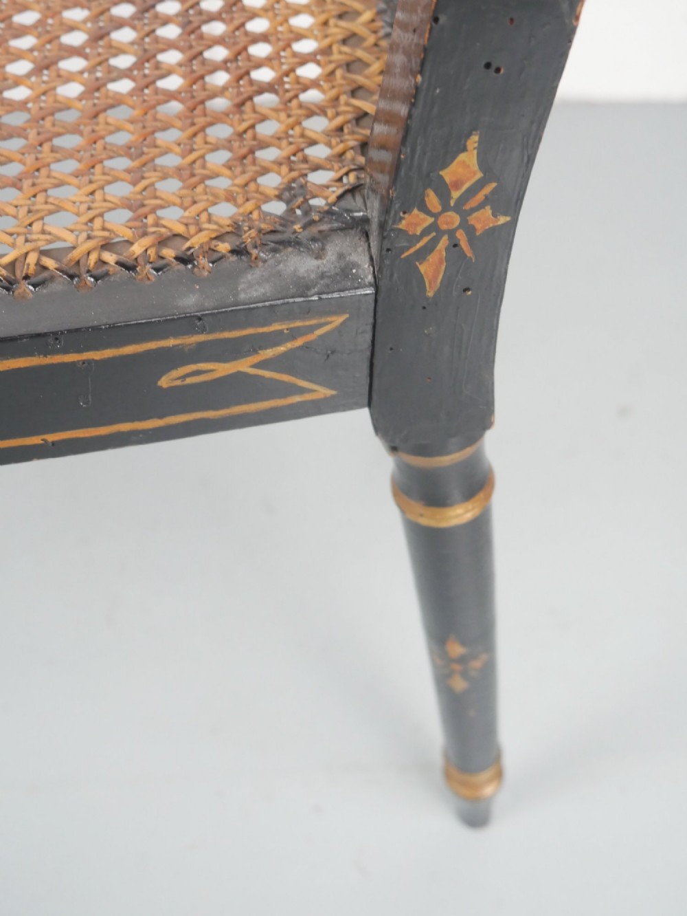 A black painted and parcel-gilt antique Sheraton window seat featuring pointed arch end splats and a floral needlepoint cushion. View X