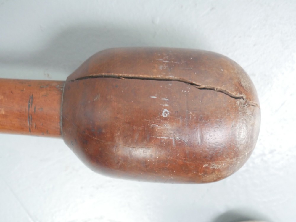 A large turned wooden mortar with ribbed bands on its exterior and a matching pestle resting inside. View VI