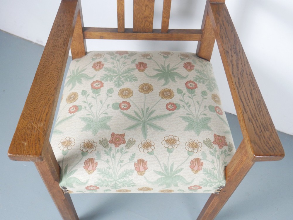 An Arts and Crafts style medium oak armchair featuring vertical back slats, flat armrests, and floral pattern upholstery with brass stud trim. View II