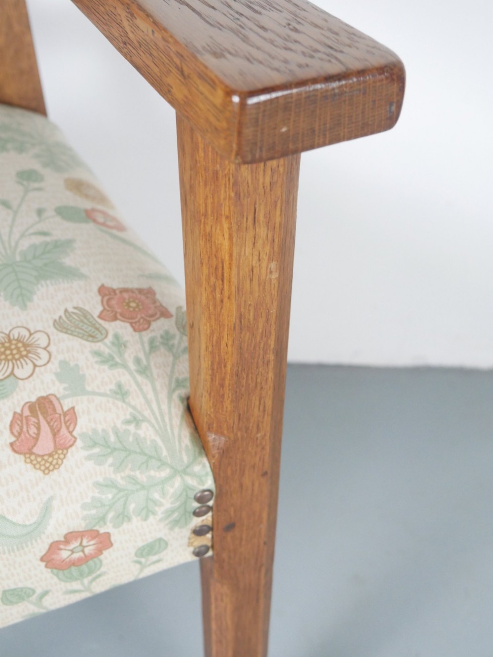 An Arts and Crafts style medium oak armchair featuring vertical back slats, flat armrests, and floral pattern upholstery with brass stud trim. View IV