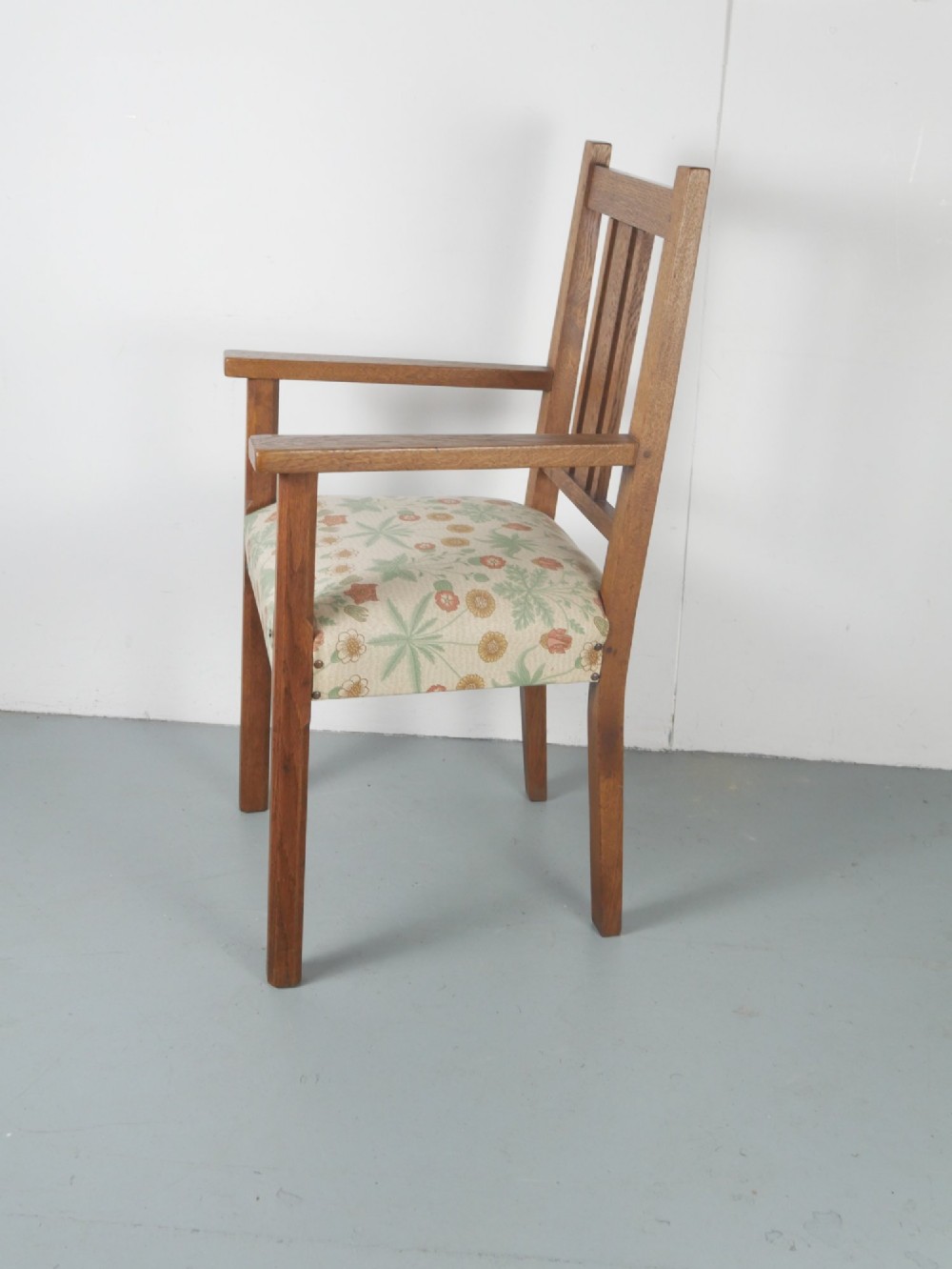 An Arts and Crafts style medium oak armchair featuring vertical back slats, flat armrests, and floral pattern upholstery with brass stud trim. View VII