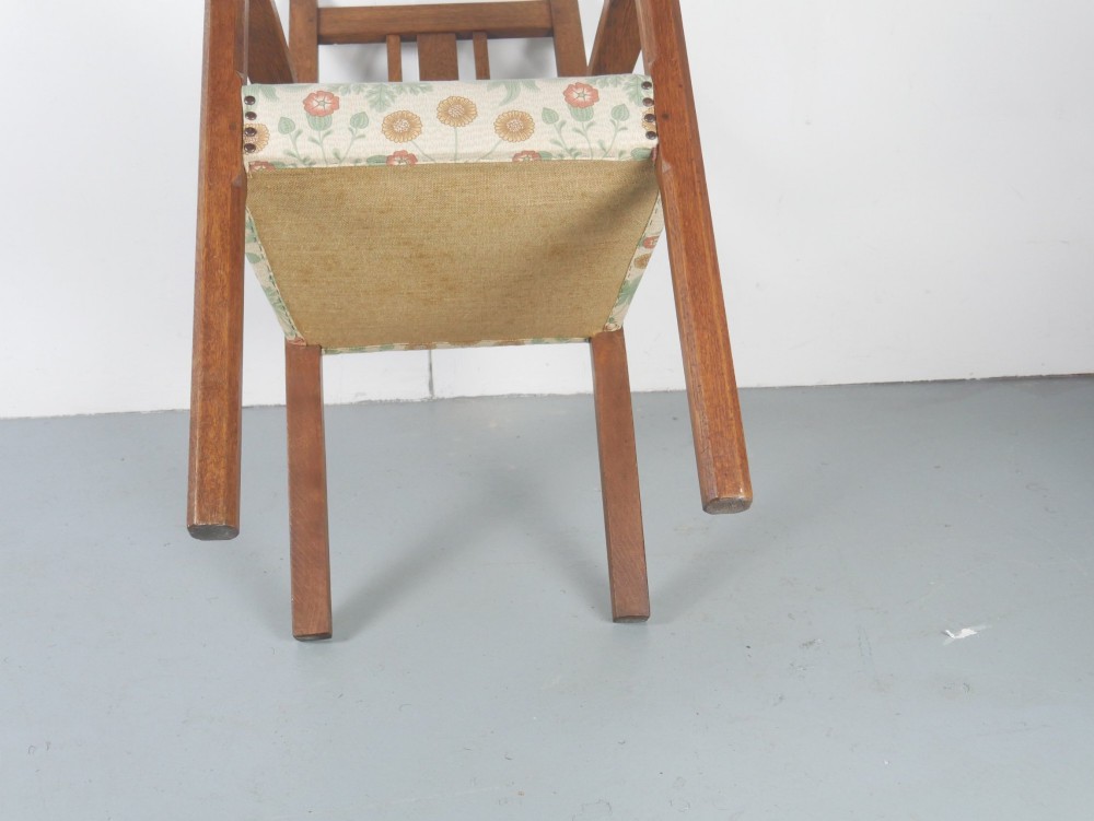 An Arts and Crafts style medium oak armchair featuring vertical back slats, flat armrests, and floral pattern upholstery with brass stud trim. View IX