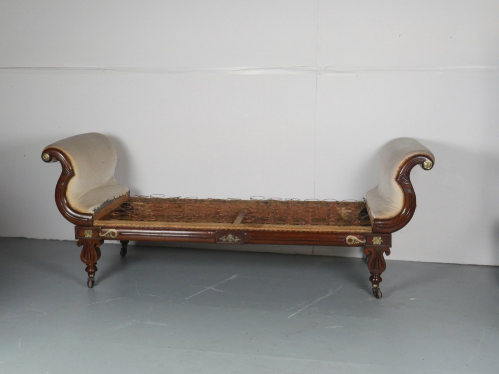 An early nineteenth-century Regency mahogany scroll-ended sofa frame featuring brass mounts, reeded turned legs on brass castors, and upholstered end scrolls with exposed spring seating. View VII