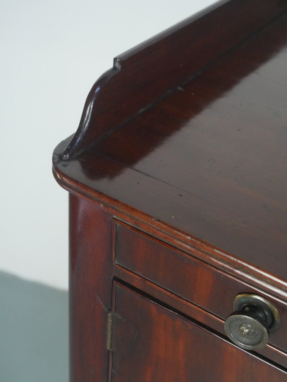 A matched pair of dark mahogany Regency bedside cupboards featuring gallery tops, single cupboard doors, lower drawers, reeded legs, and brass castors. View VI