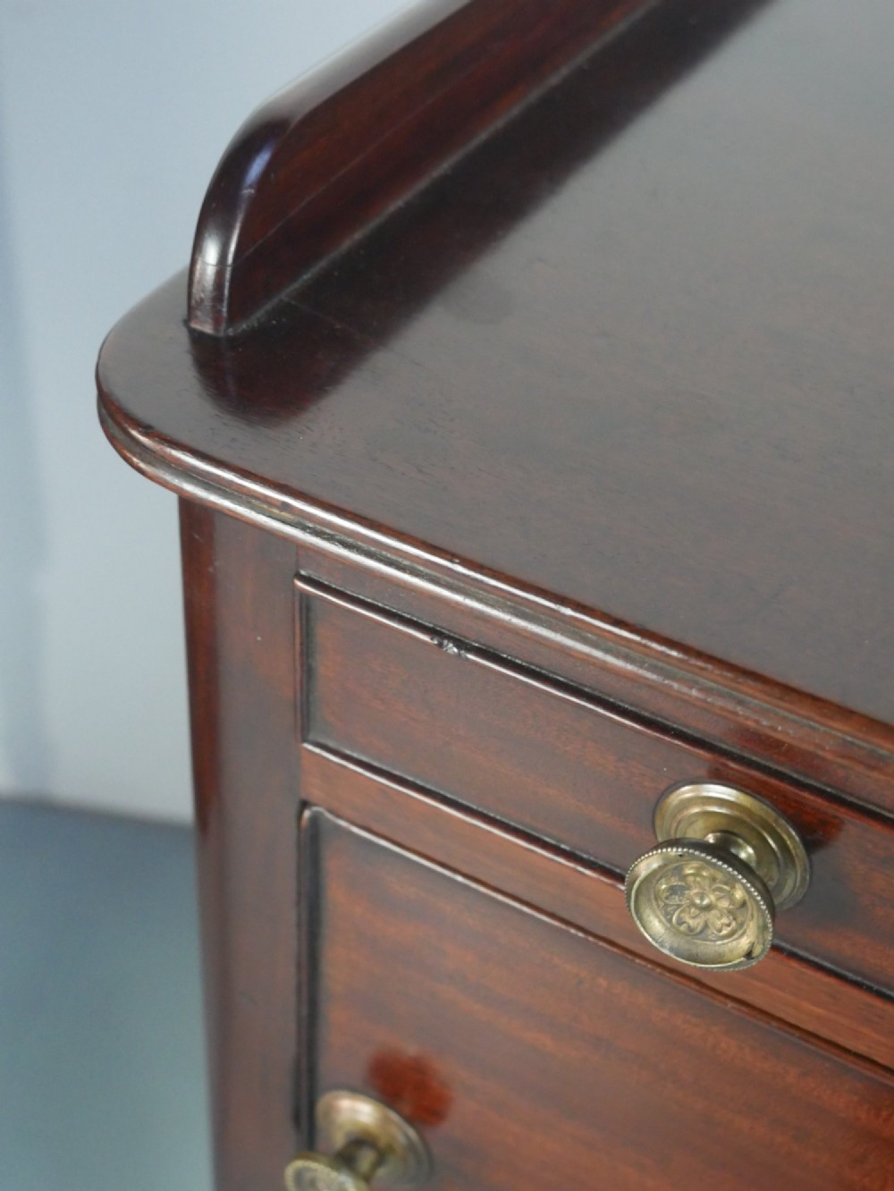 A matched pair of dark mahogany Regency bedside cupboards featuring gallery tops, single cupboard doors, lower drawers, reeded legs, and brass castors. View VII