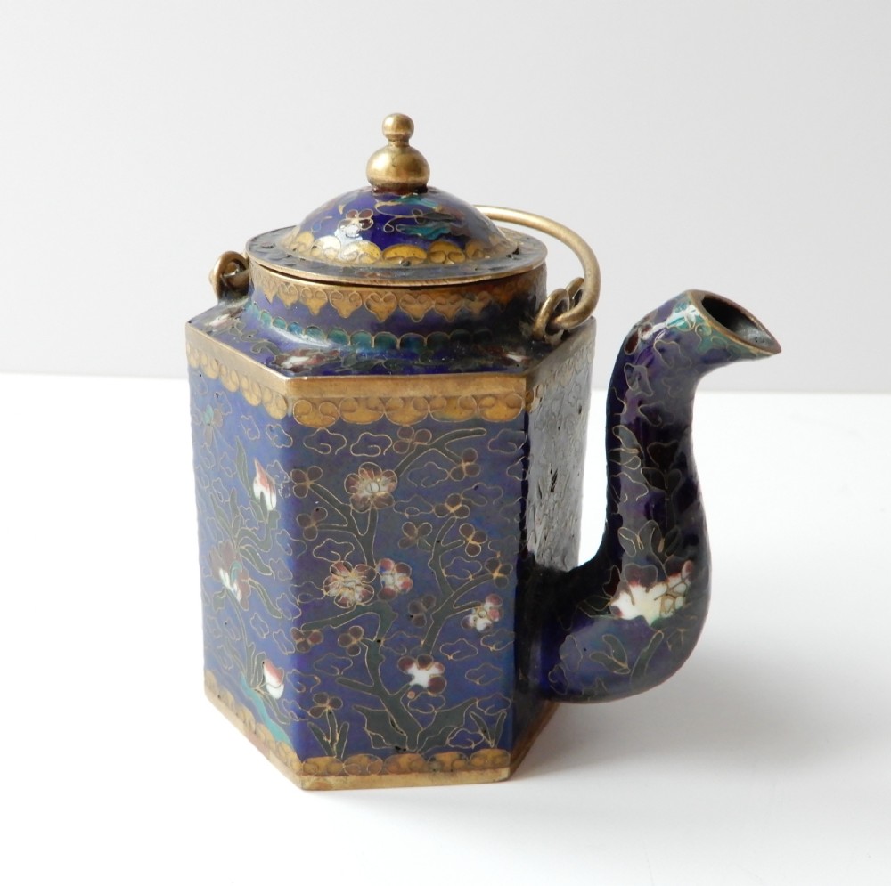 A hexagonal Chinese cloisonne enamel teapot featuring a navy blue body with floral motifs, gold wirework, and a fitted brass lid.