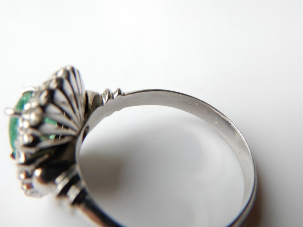 An oval green emerald set in a 14ct white gold ring surrounded by a double halo of brilliant cut diamonds. View VIII