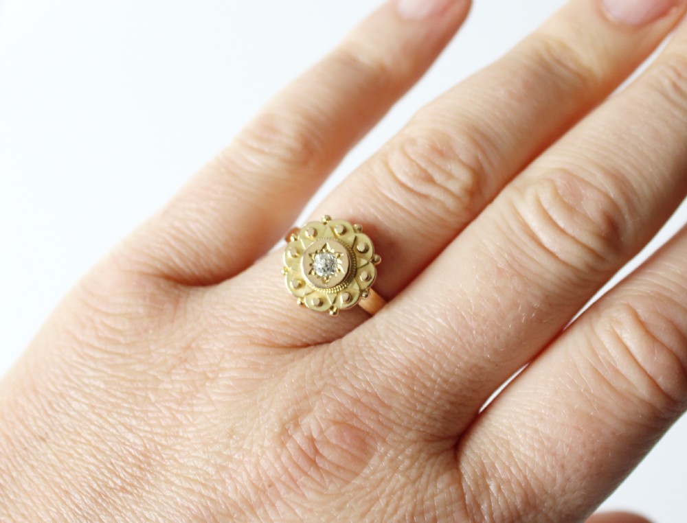An antique 9ct yellow gold ring featuring a central star-set diamond surrounded by intricate Etruscan revival beaded and scalloped detail. View V