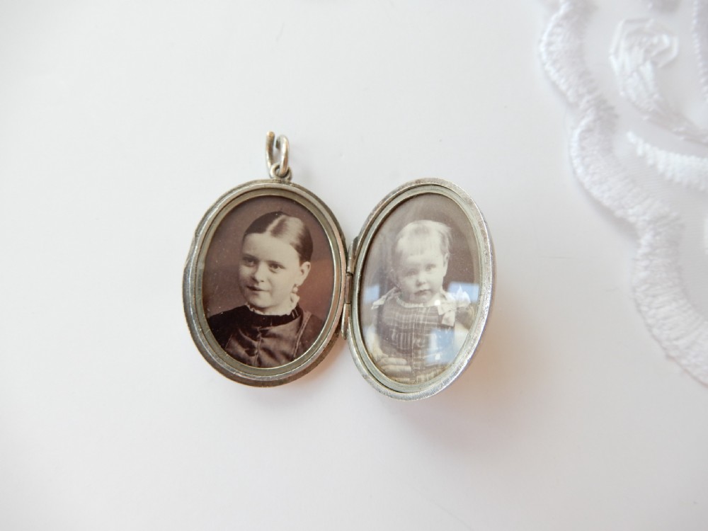 An oval sterling silver locket featuring a hand-engraved bird perched on foliage. View V
