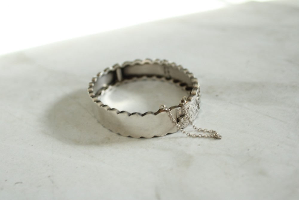 Victorian sterling silver hinged bangle with scalloped borders and applied foliate engraving. View IV