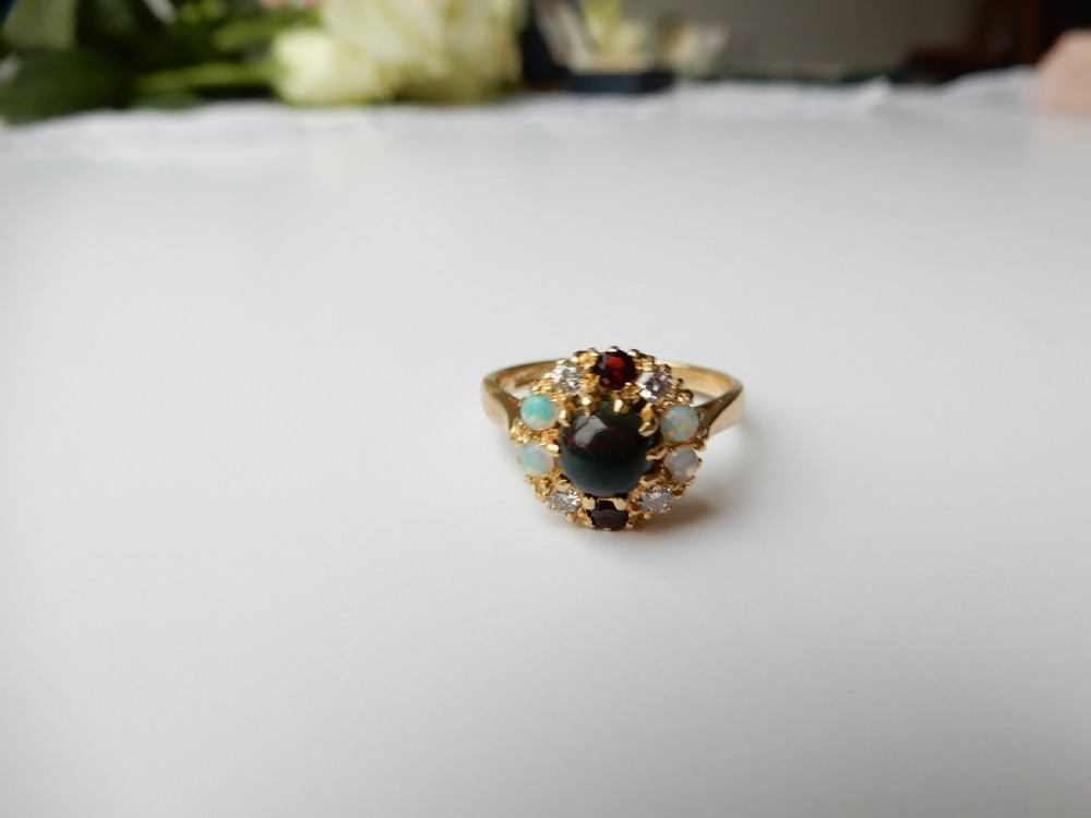 An antique yellow gold cluster ring set with a central cabochon bloodstone surrounded by alternating opals, garnets, and diamonds. View II