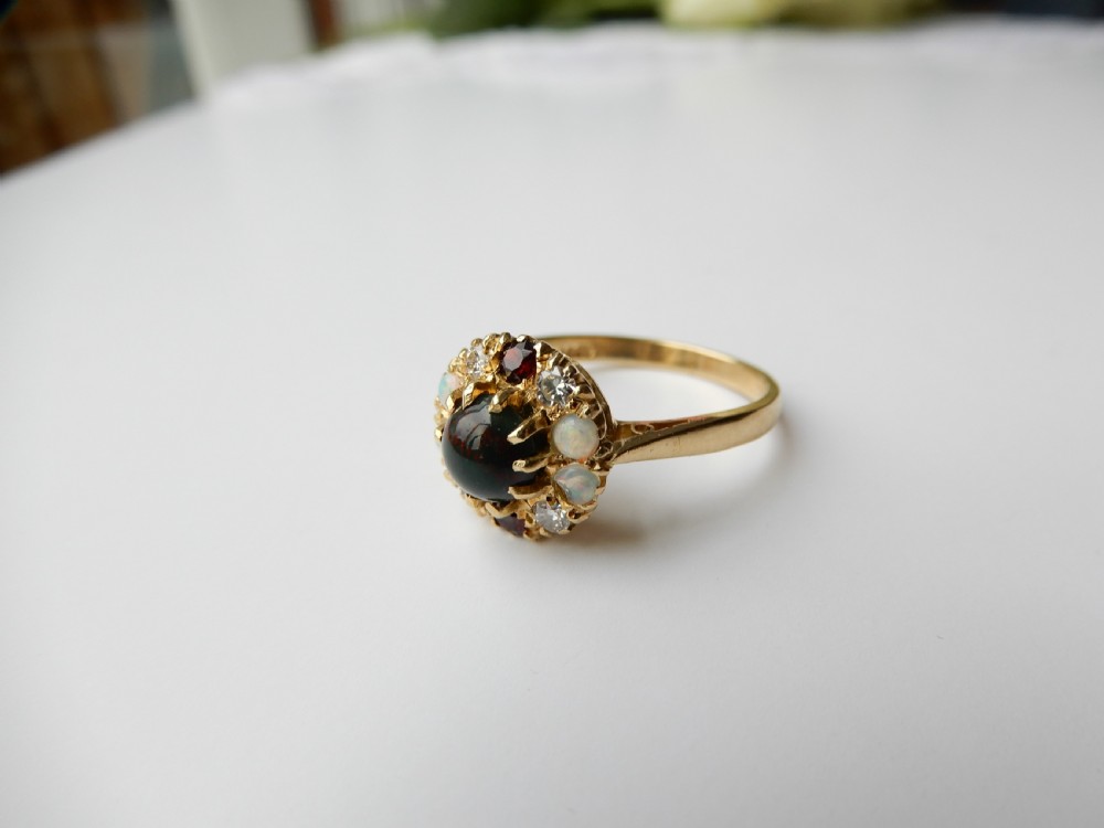 An antique yellow gold cluster ring set with a central cabochon bloodstone surrounded by alternating opals, garnets, and diamonds. View IV