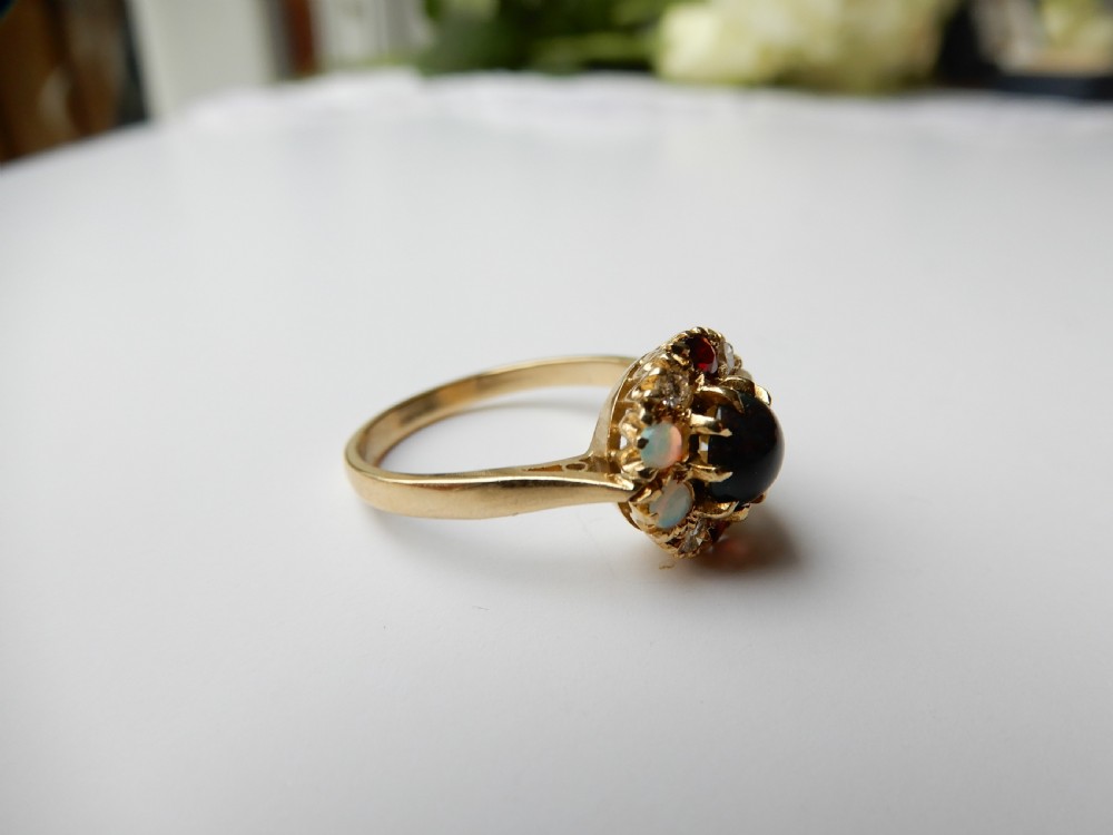 An antique yellow gold cluster ring set with a central cabochon bloodstone surrounded by alternating opals, garnets, and diamonds. View V