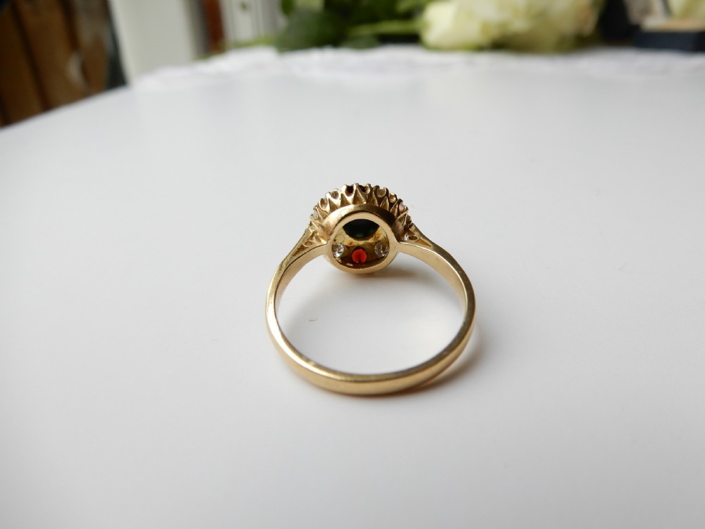 An antique yellow gold cluster ring set with a central cabochon bloodstone surrounded by alternating opals, garnets, and diamonds. View VII