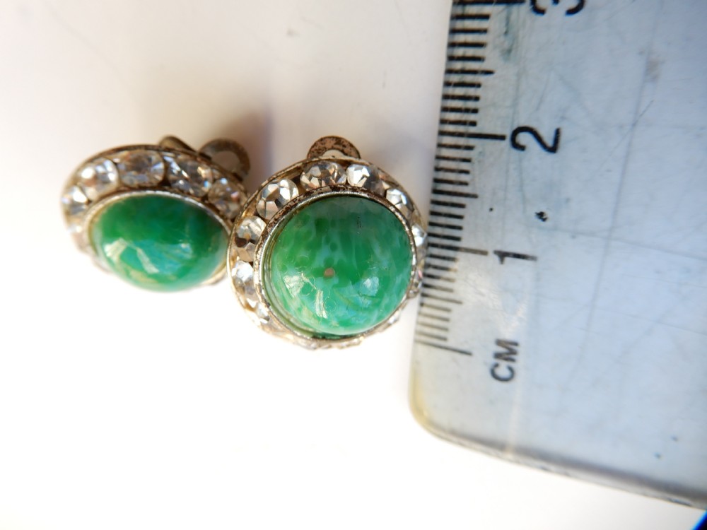 A pair of circular clip-on earrings featuring domed green Peking glass cabochons bordered by a halo of clear rhinestones in silver-tone settings. View IV
