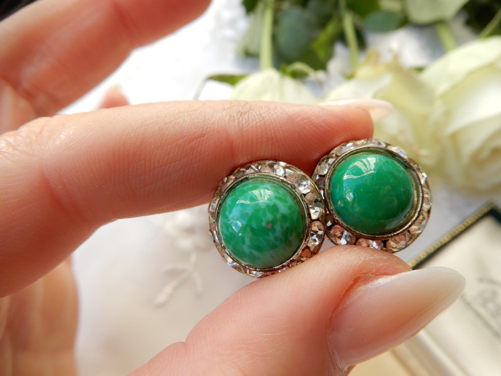 A pair of circular clip-on earrings featuring domed green Peking glass cabochons bordered by a halo of clear rhinestones in silver-tone settings. View V