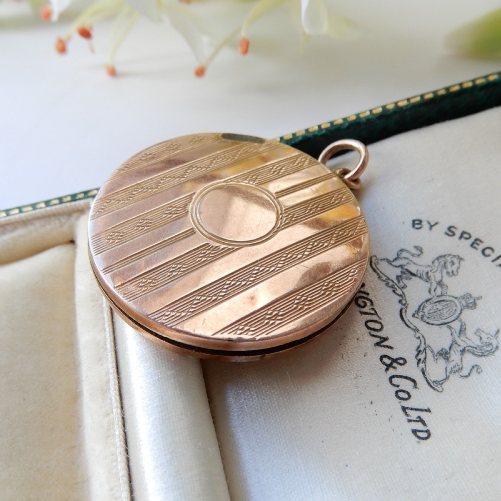 A round 9ct gold back and front locket featuring engine-turned diagonal line engraving and an unengraved central circular cartouche.